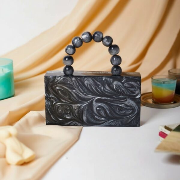 Black and silver box clutch with round resin handle.