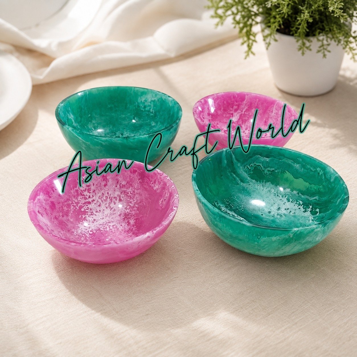 Set of four handcrafted resin bowls in marbled pink and emerald green by ACW, displayed on a beige table. Alternative Alt Text Options (by Use Cas